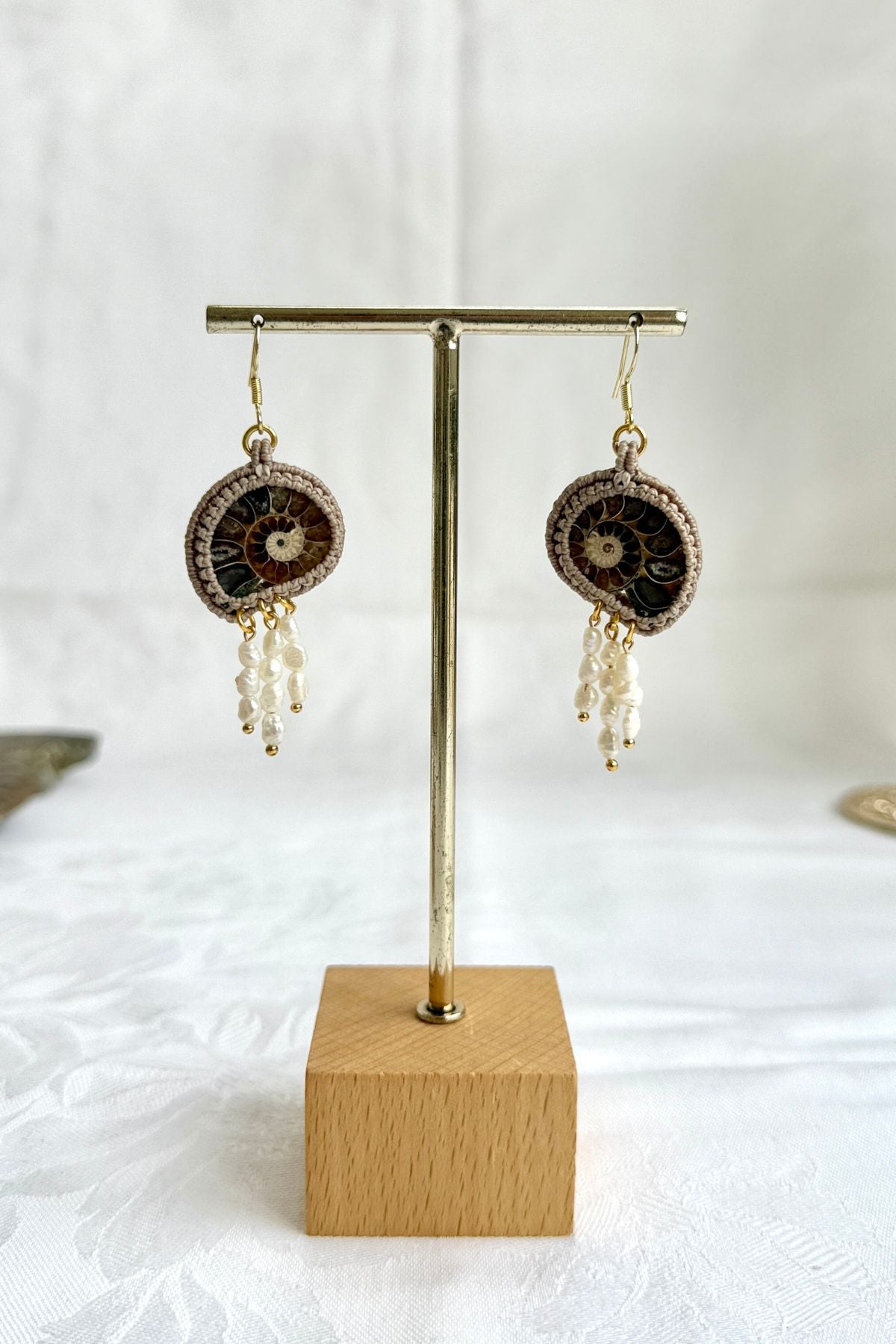 Sliced ammonite drop earrings on display, natural fossils with flowing pearl accents, one of a kind design