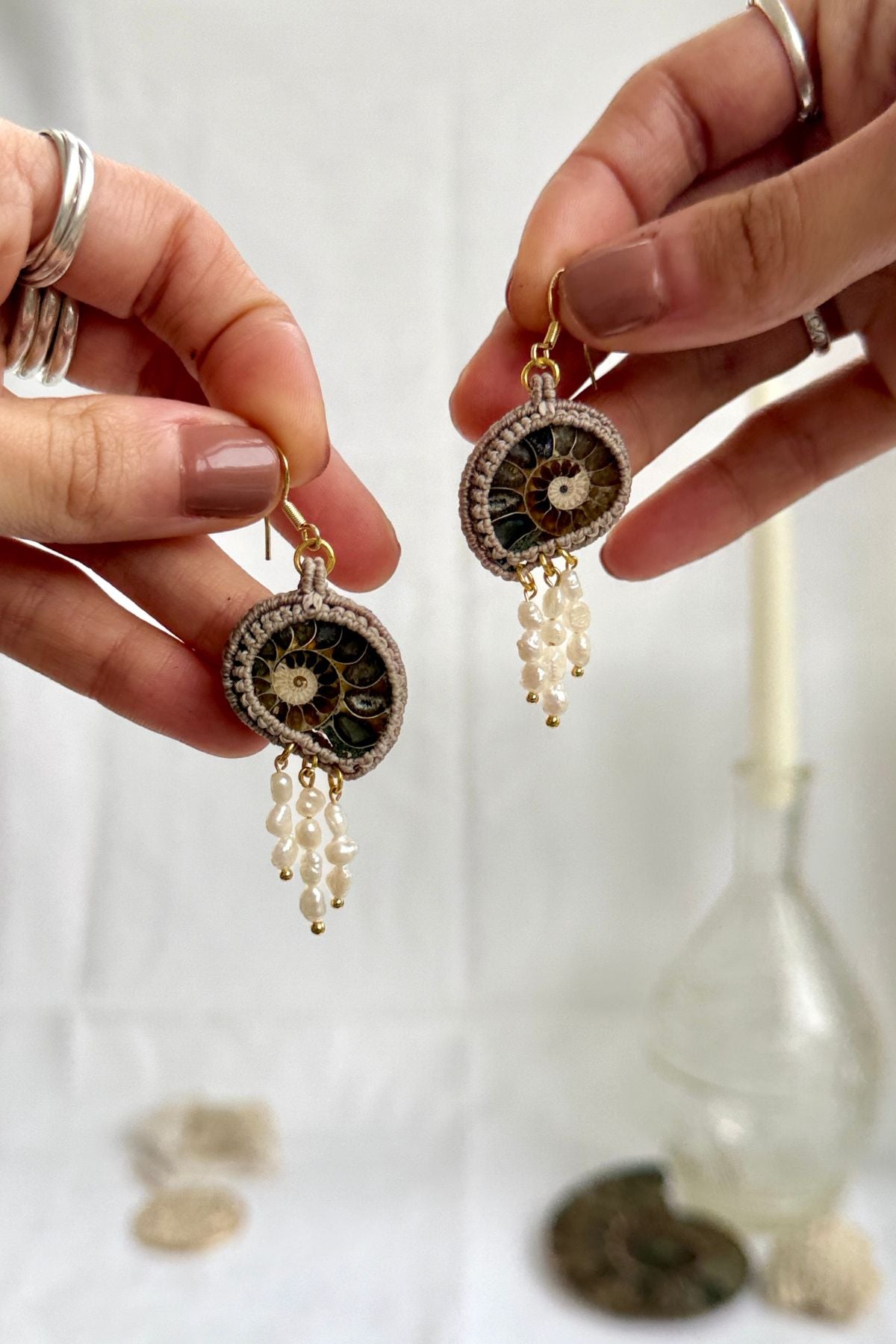 Sliced ammonite earrings shown in hand, highlighting natural freshwater pearl drops and fluid movement