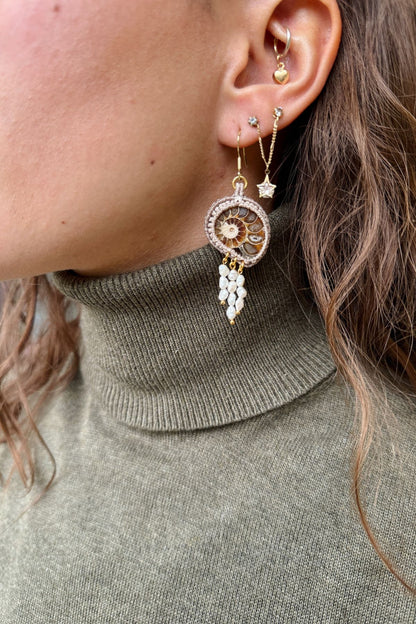 Detailed view of sliced ammonite earrings on model, showing pearl drops and asymmetric movement