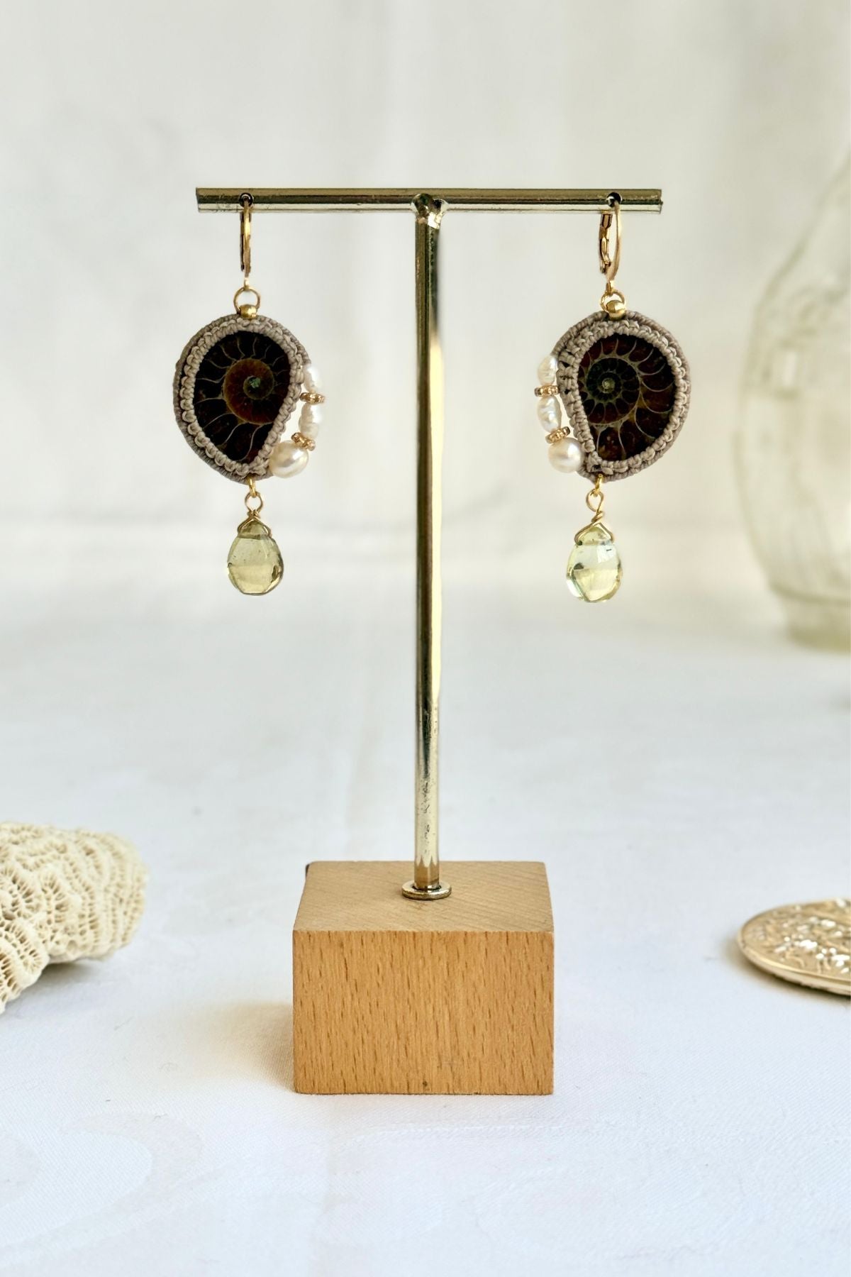 Ammonite fossil hoop drop earrings displayed on stand with freshwater pearls and lemon quartz accents