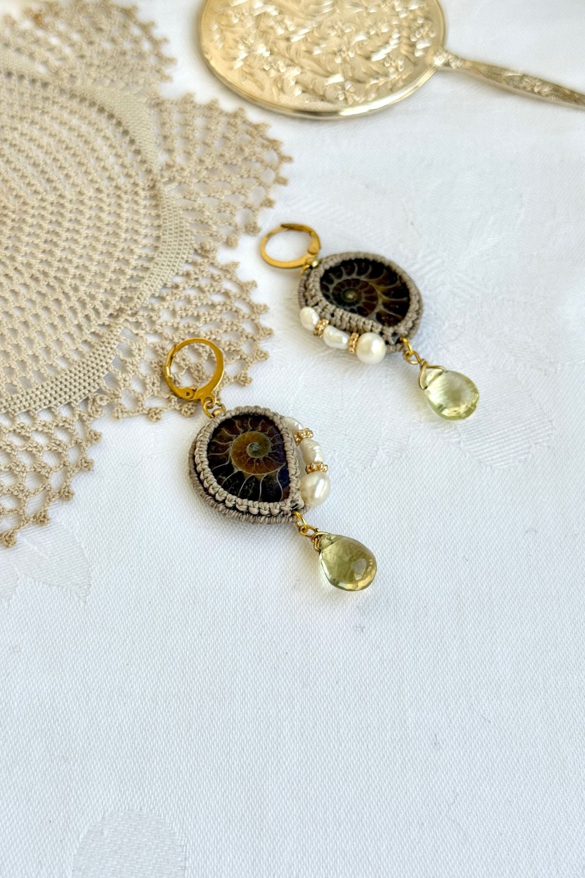 Close-up of genuine ammonite fossil earrings with freshwater pearls and translucent lemon quartz drops