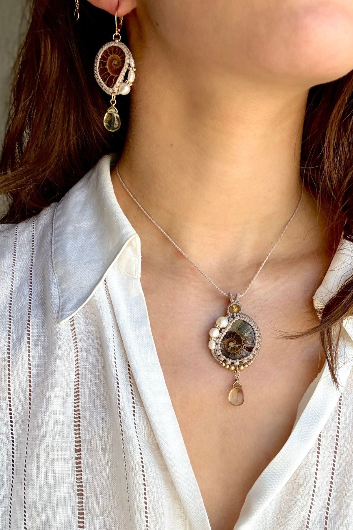 Model wearing asymmetric ammonite fossil and pearl hoop earrings with matching ocean inspired necklace