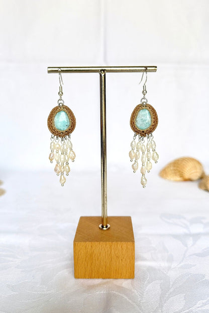 Front view of Larimar dangle earrings with beige macrame surrounds and cascading freshwater pearls.