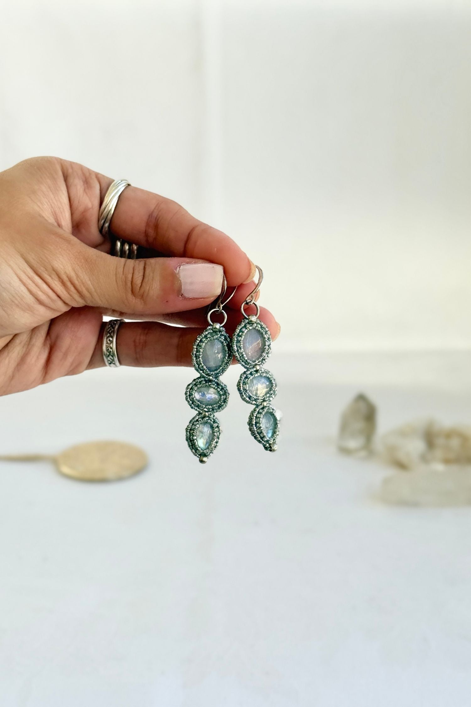 Hand holding the handmade Moonstone earrings, highlighting the intricate macrame work and the natural glow of the gemstones.
