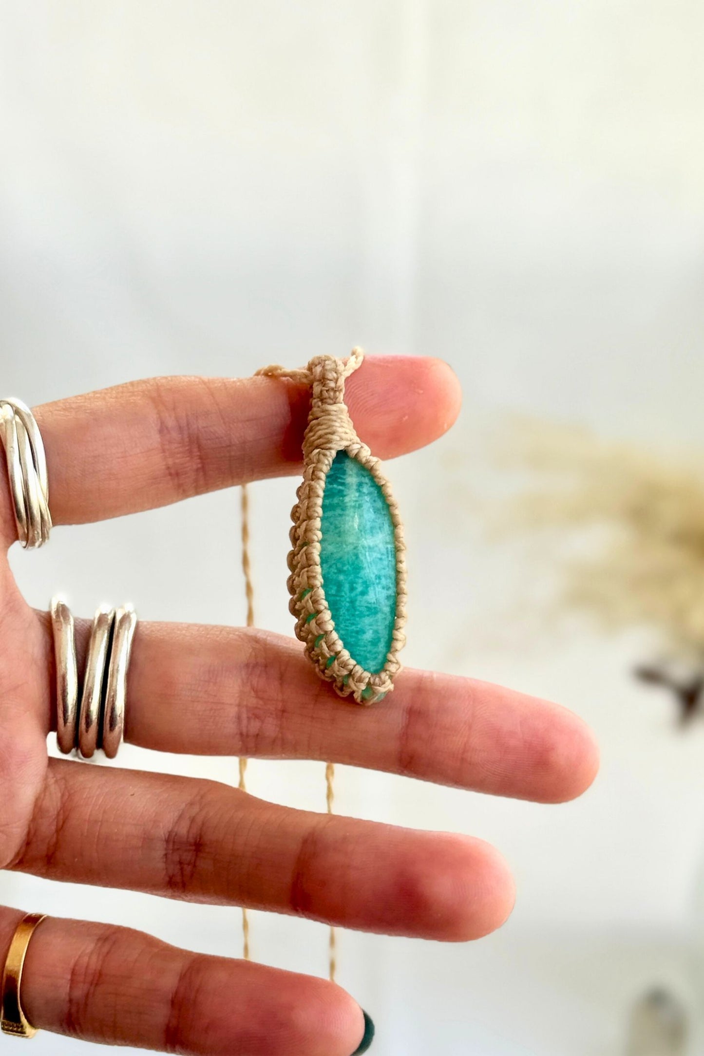 Hand holding a handmade Amazonite Macrame necklace from the Essence collection, featuring a high-quality gemstone in a delicate everyday-wear design.