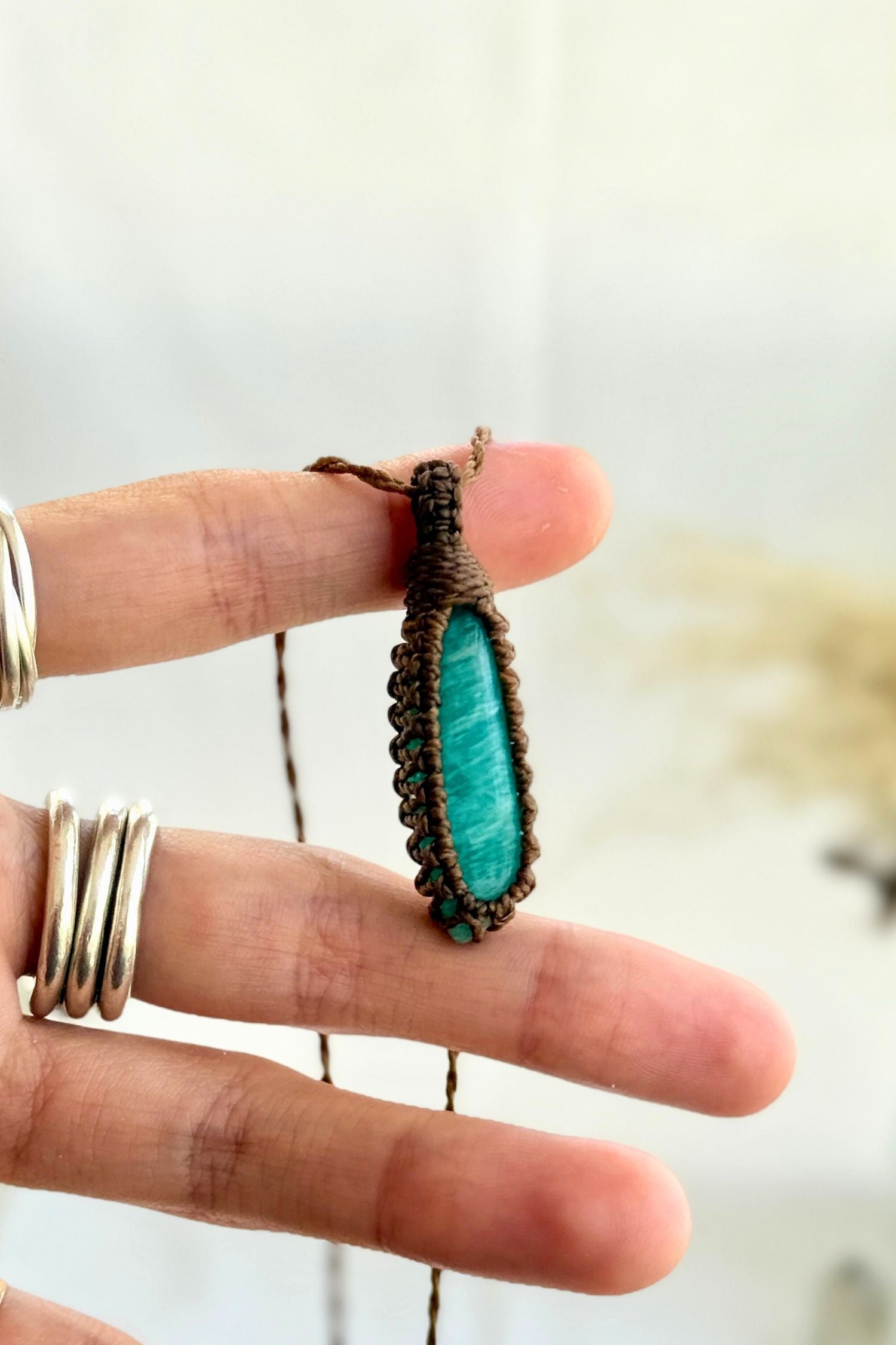Hand holding a handmade Amazonite Macrame necklace from the Essence collection, featuring a high-quality gemstone in a delicate everyday-wear design.