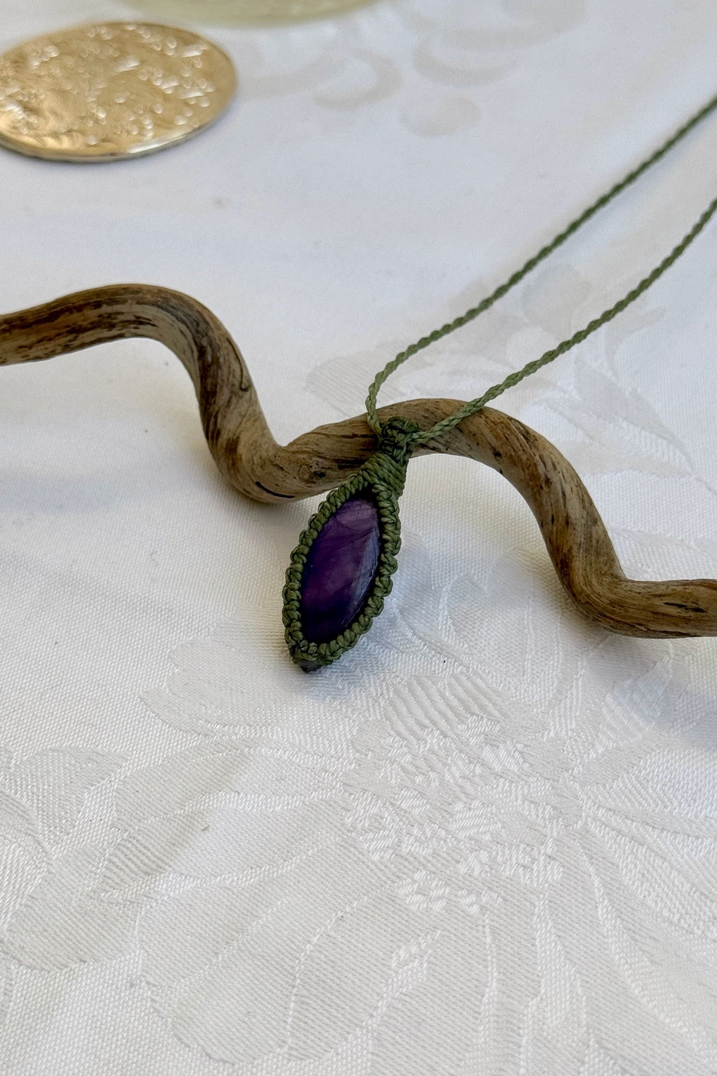 Side angle view of the Amethyst Macrame necklace, showing the fine macrame details and the unique gemstone centerpiece.