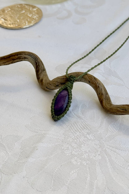 Side angle view of the Amethyst Macrame necklace, showing the fine macrame details and the unique gemstone centerpiece.