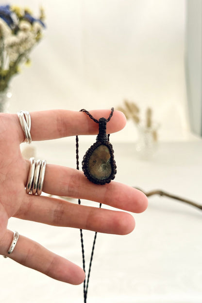 Handmade Ammonite macramé necklace held in hand, delicate natural fossil jewelry