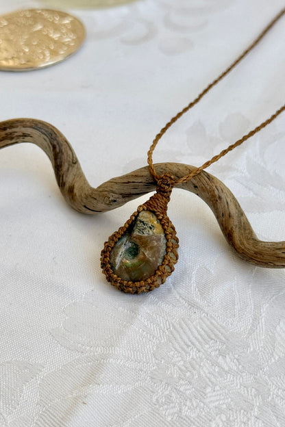 Side angle view of the Ammonite Macrame necklace, showing the fine macrame details and the unique gemstone centerpiece.