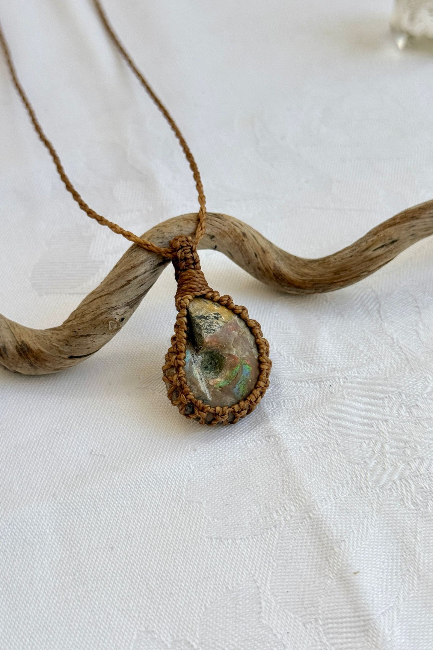 Close-up of handmade Ammonite Macrame necklace, showcasing the intricate macrame knotting and the vibrant patterns of the gemstone.