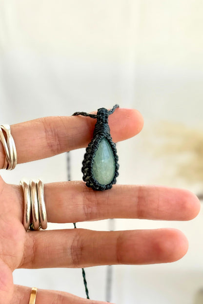 Hand holding a handmade Aquamarine Macrame necklace from the Essence collection, featuring a high-quality gemstone in a delicate everyday-wear design.