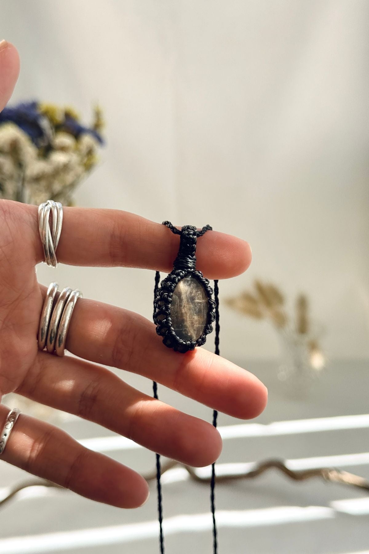 Handmade Black Moonstone macramé necklace held in hand, delicate natural gemstone jewelry