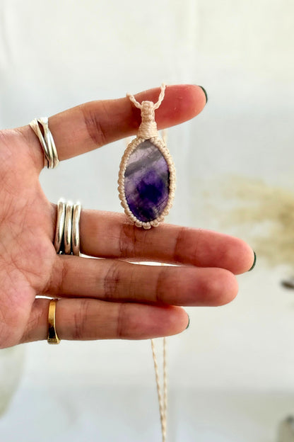 Hand holding a handmade Chevron Amethyst Macrame necklace from the Essence collection, featuring a high-quality gemstone in a delicate everyday-wear design.