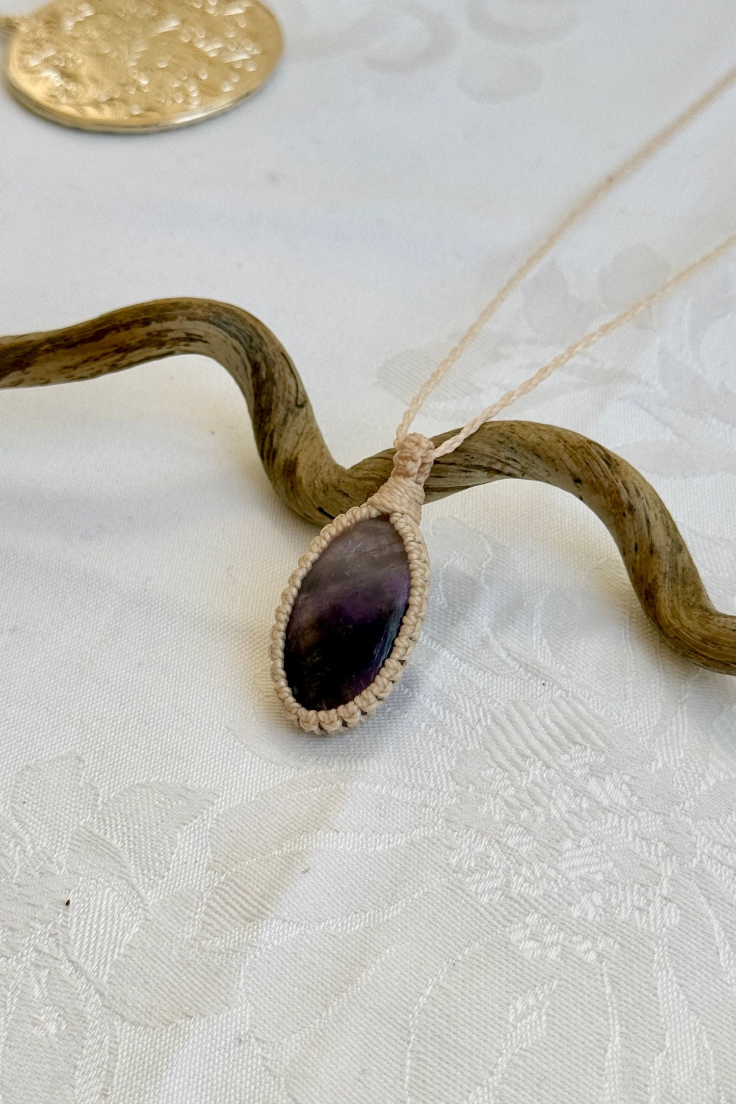 Side angle view of the Chevron Amethyst Macrame necklace, showing the fine macrame details and the unique gemstone centerpiece.