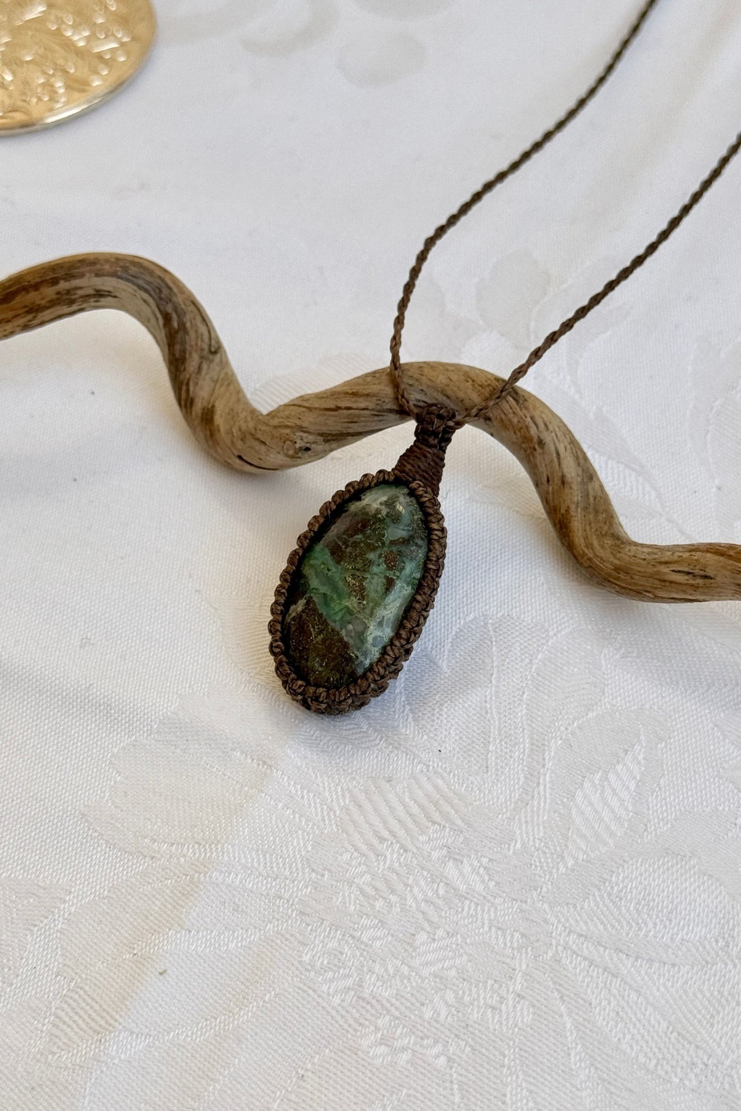 Side angle view of the Chrysocolla Macrame necklace, showing the fine macrame details and the unique gemstone centerpiece.