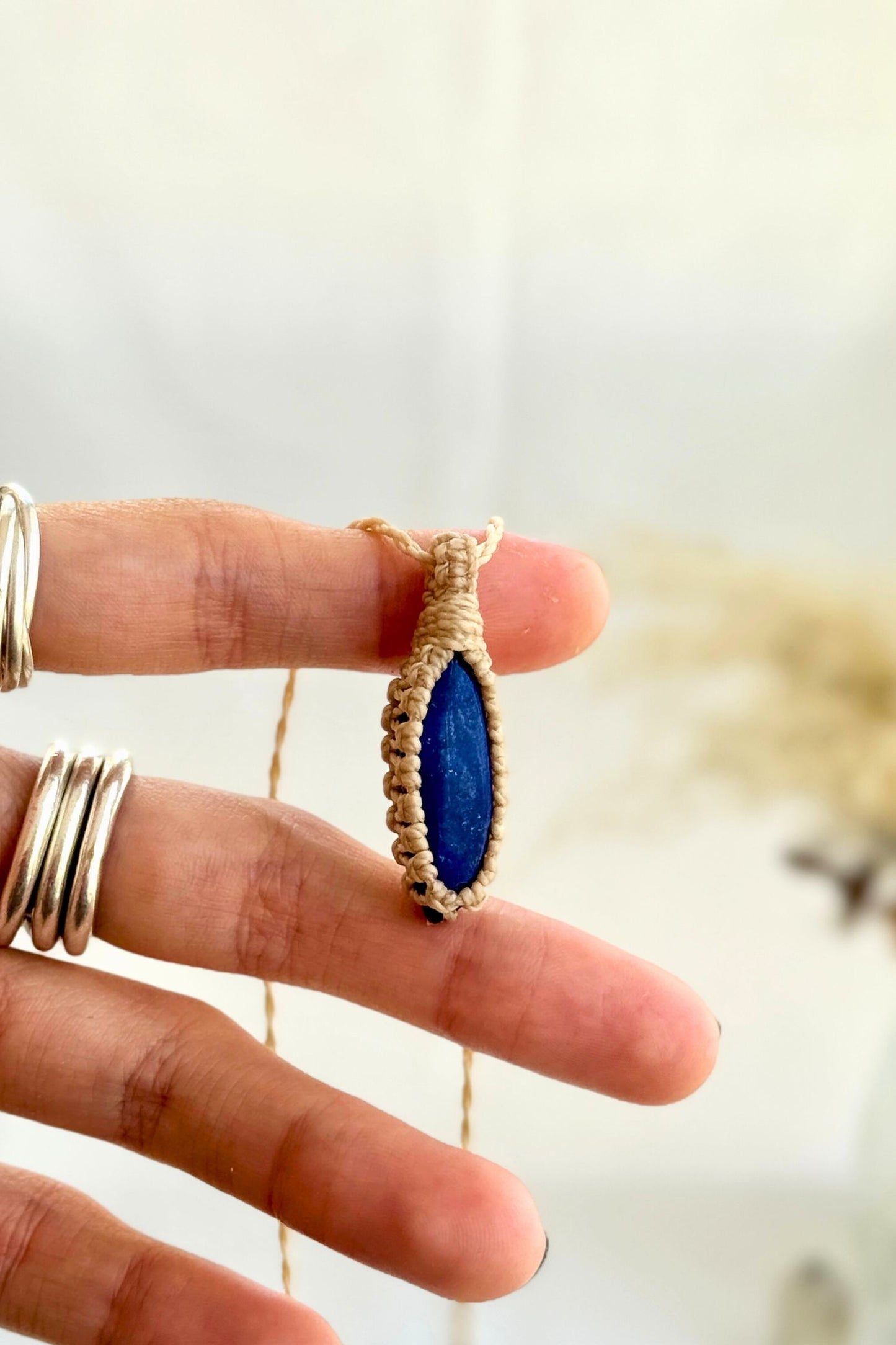 Hand holding a handmade Lapis Lazuli Macrame necklace from the Essence collection, featuring a high-quality gemstone in a delicate everyday-wear design.