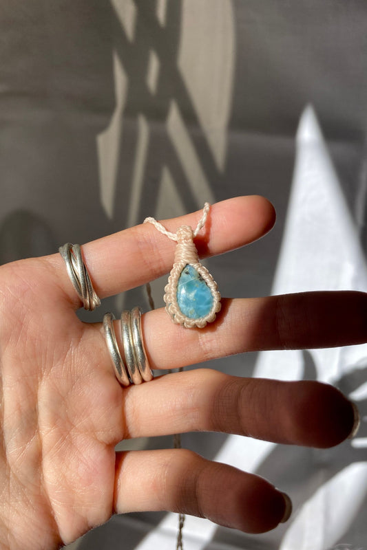 Hand holding a handmade Larimar Macrame necklace from the Essence collection, featuring a high-quality blue gemstone in a delicate everyday-wear design.