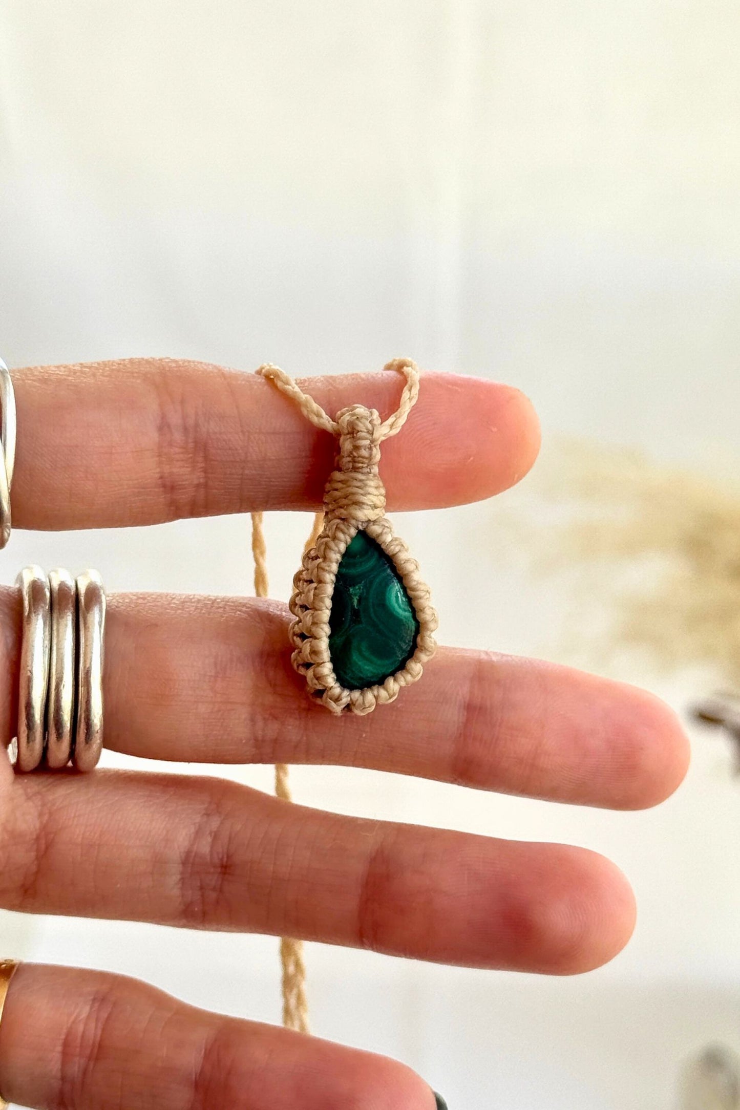 Hand holding a handmade Malachite Macrame necklace from the Essence collection, featuring a high-quality gemstone in a delicate everyday-wear design.