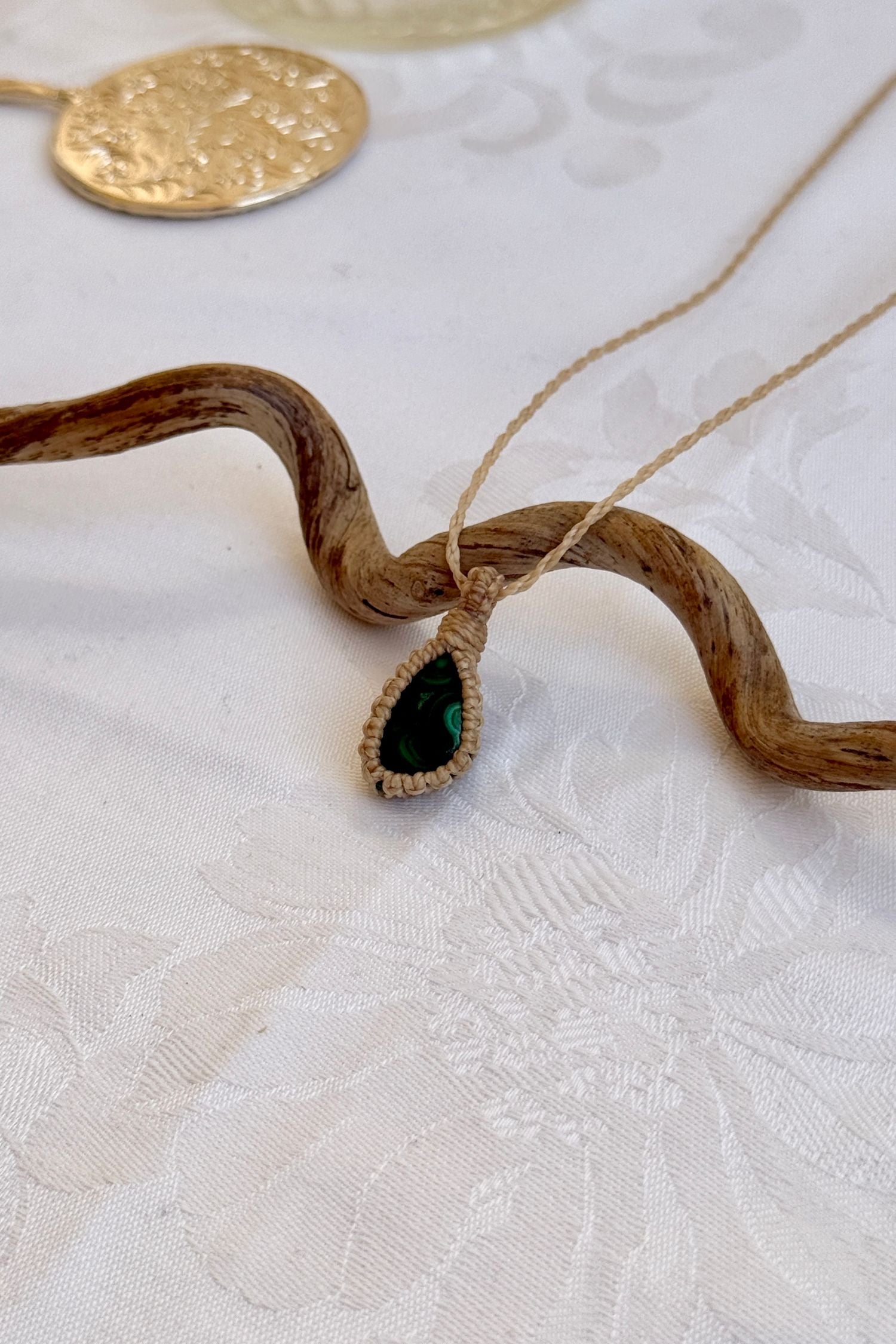 Side angle view of the Malachite Macrame necklace, showing the fine macrame details and the unique gemstone centerpiece.