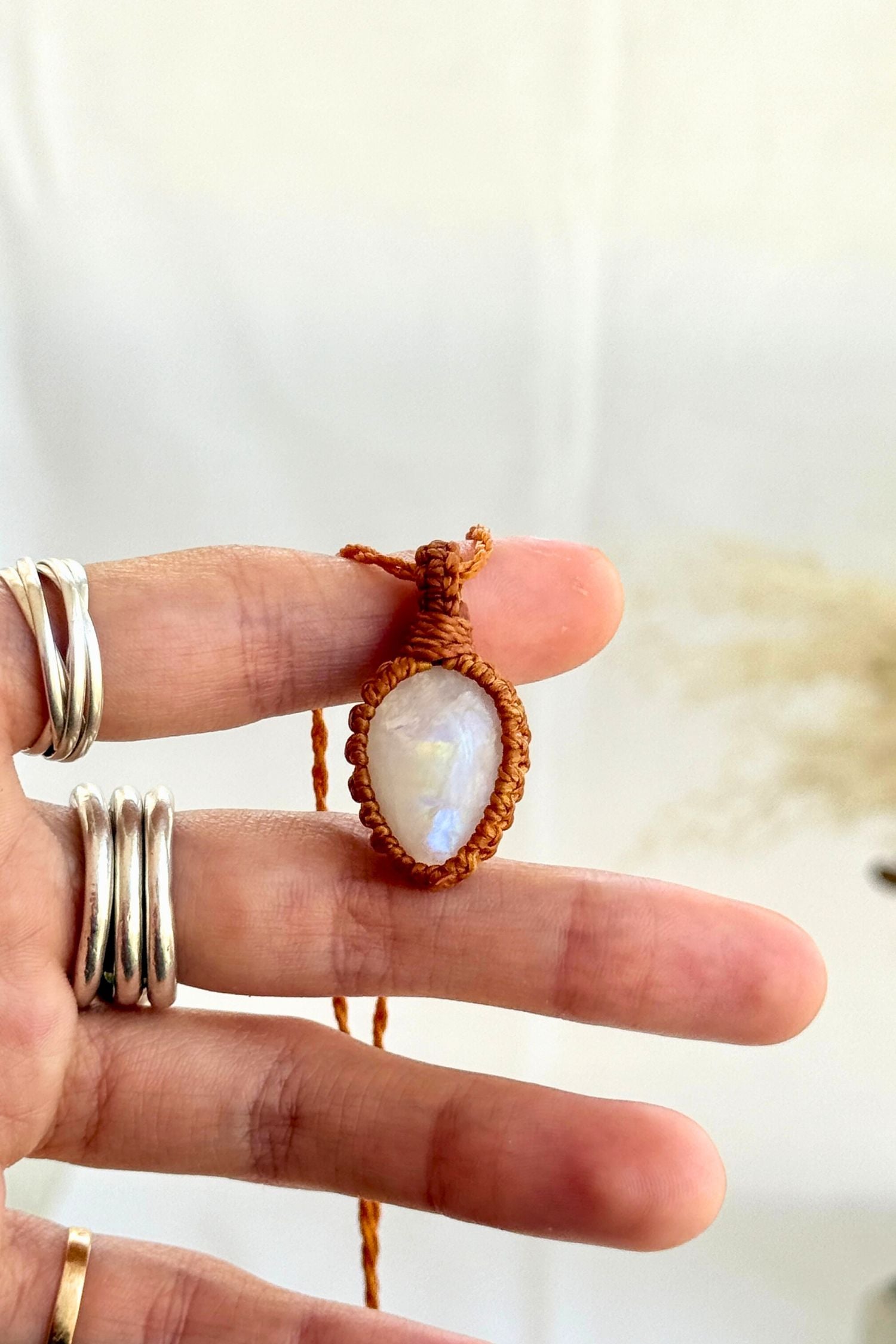 Hand holding a handmade Moonstone Macrame necklace from the Essence collection, featuring a high-quality gemstone in a delicate everyday-wear design.