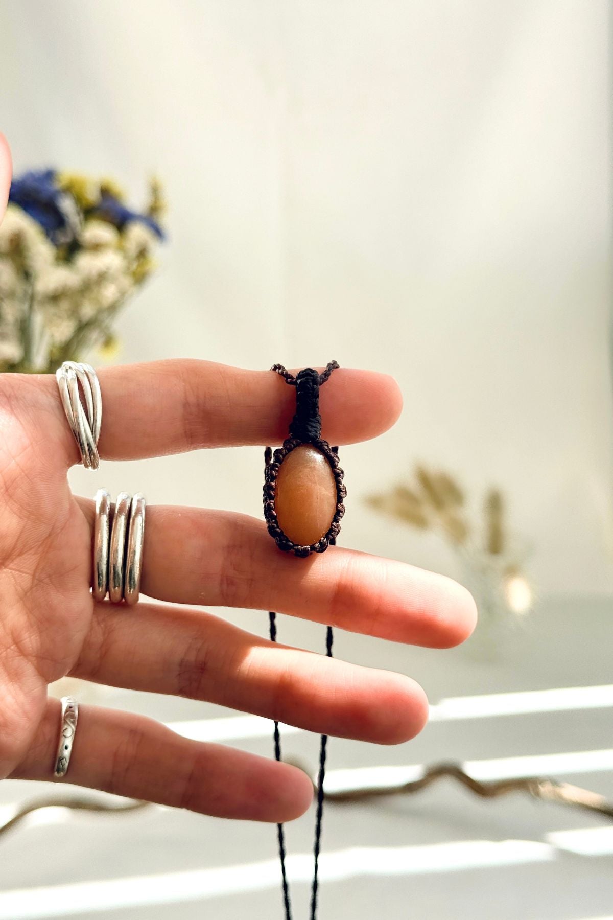 Handmade Peach Moonstone macramé necklace held in hand, delicate natural gemstone jewelry