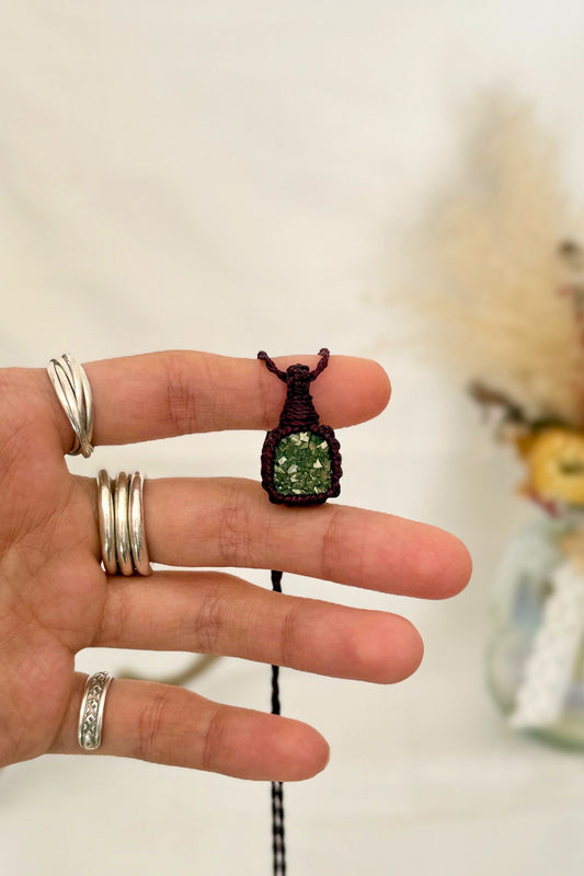 Hand holding a handmade Raw Pyrite macrame necklace with a burgundy cord, showcasing the gemstone's vibrant color holding a mysterious beauty, revealing a subtle shimmer.