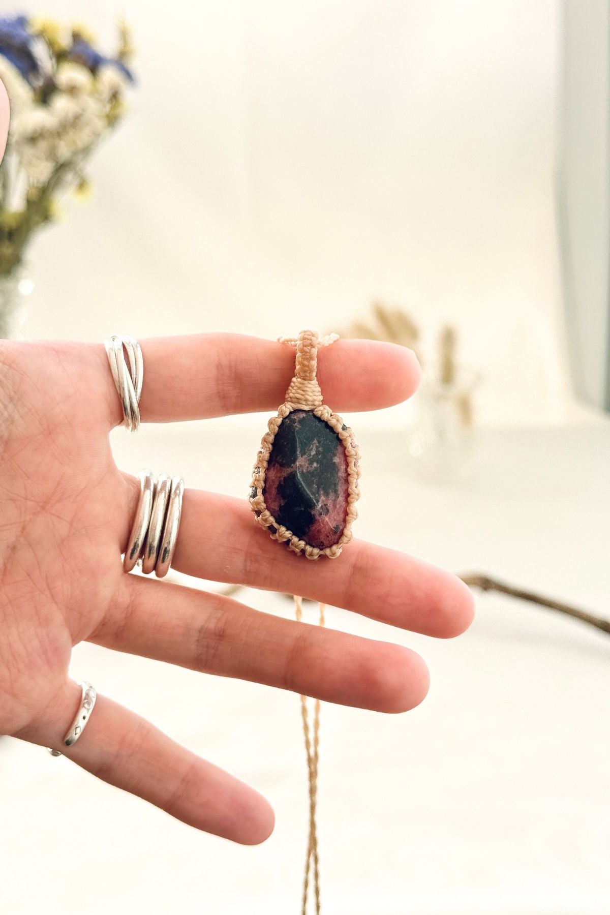 Handmade Rhodonite macramé necklace held in hand, delicate natural gemstone jewelry