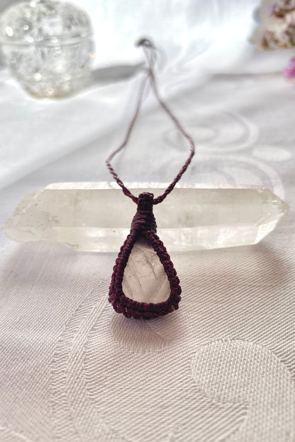 Handmade rose quartz macrame necklace laid flat, showcasing its romantic soft pink gemstone and elegant burgundy cord design.