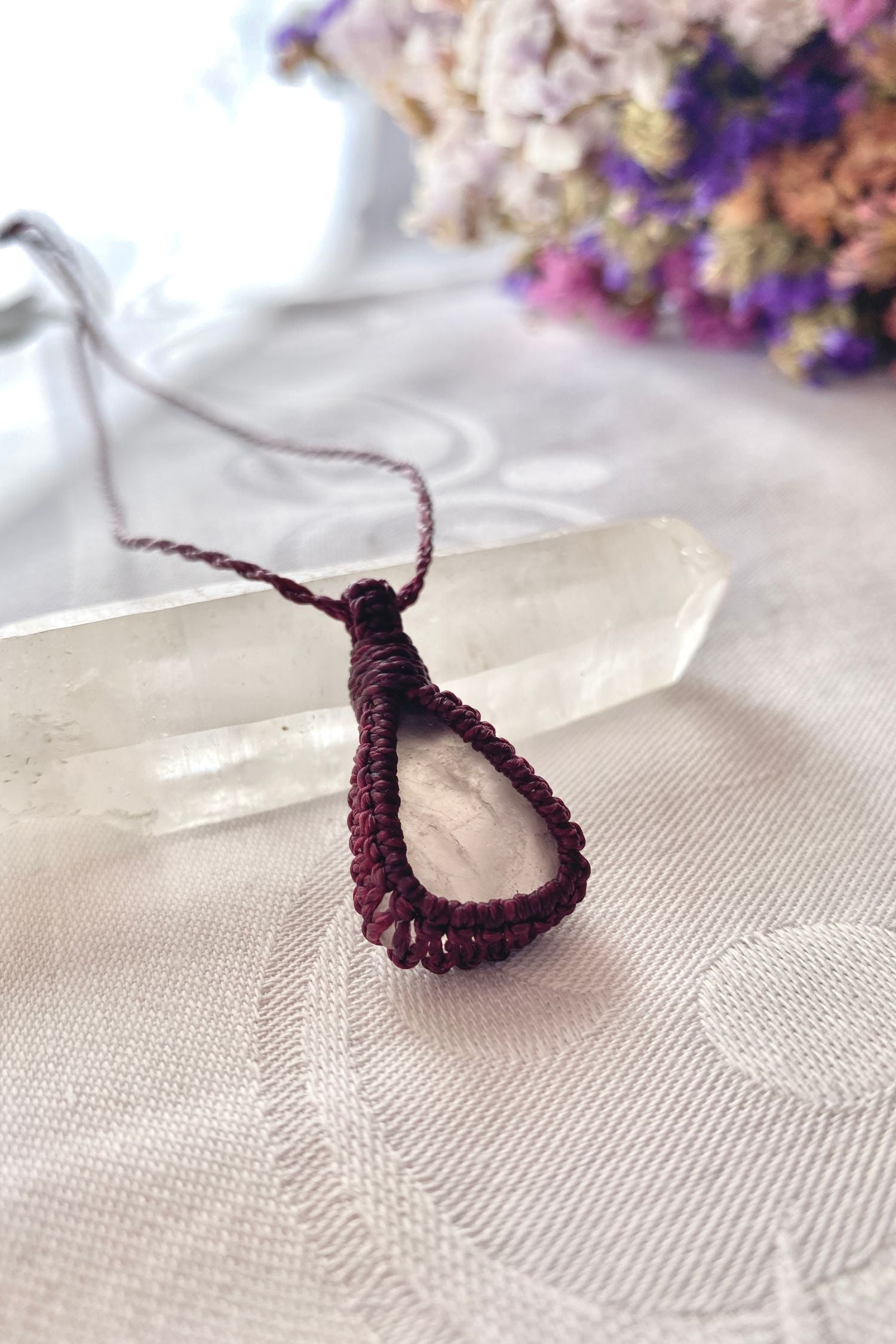 Side angle view of a handmade rose quartz macrame necklace, highlighting its intricate knotting and delicate craftsmanship.