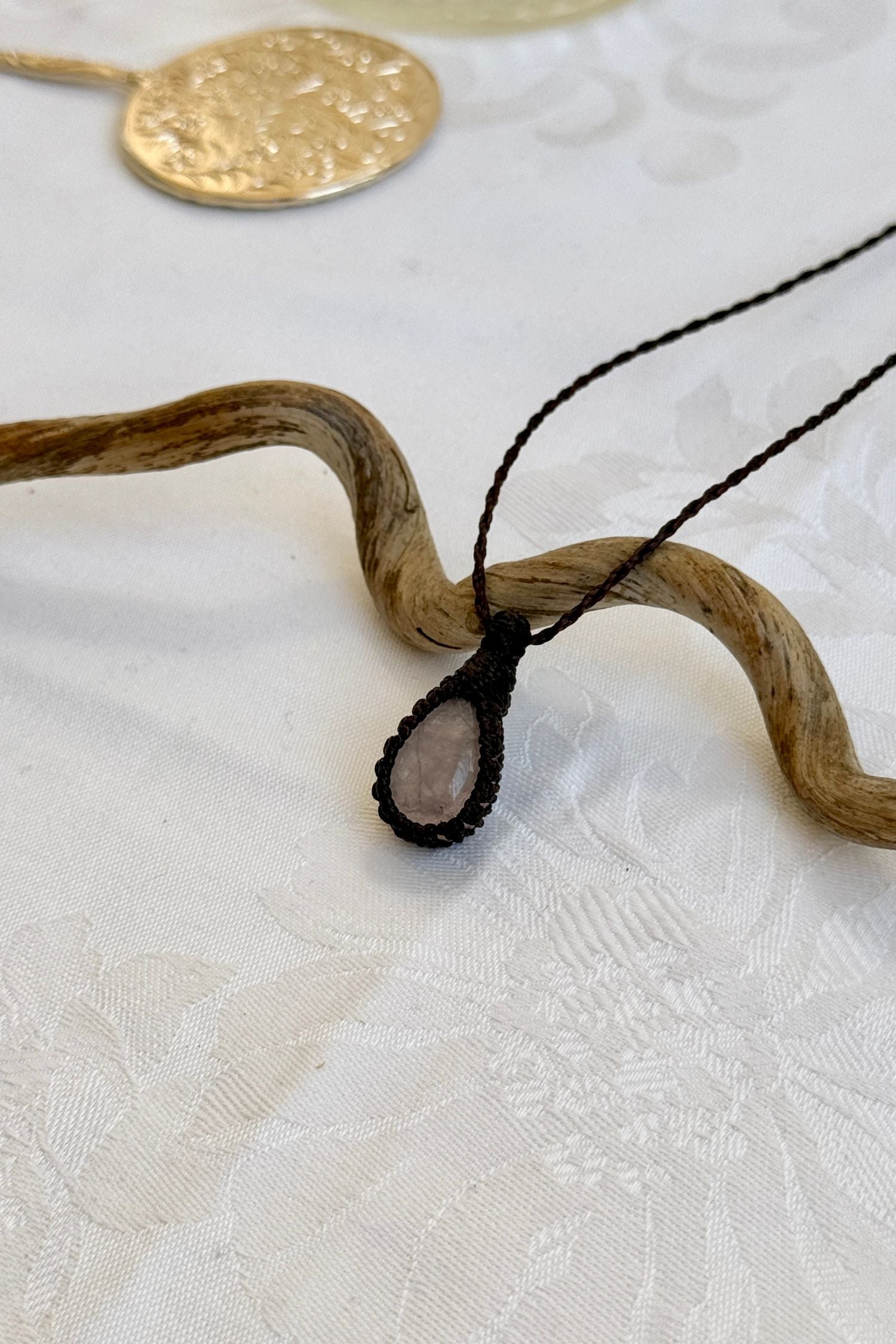 Side angle view of the Rose Quartz Macrame necklace, showing the fine macrame details and the unique gemstone centerpiece.