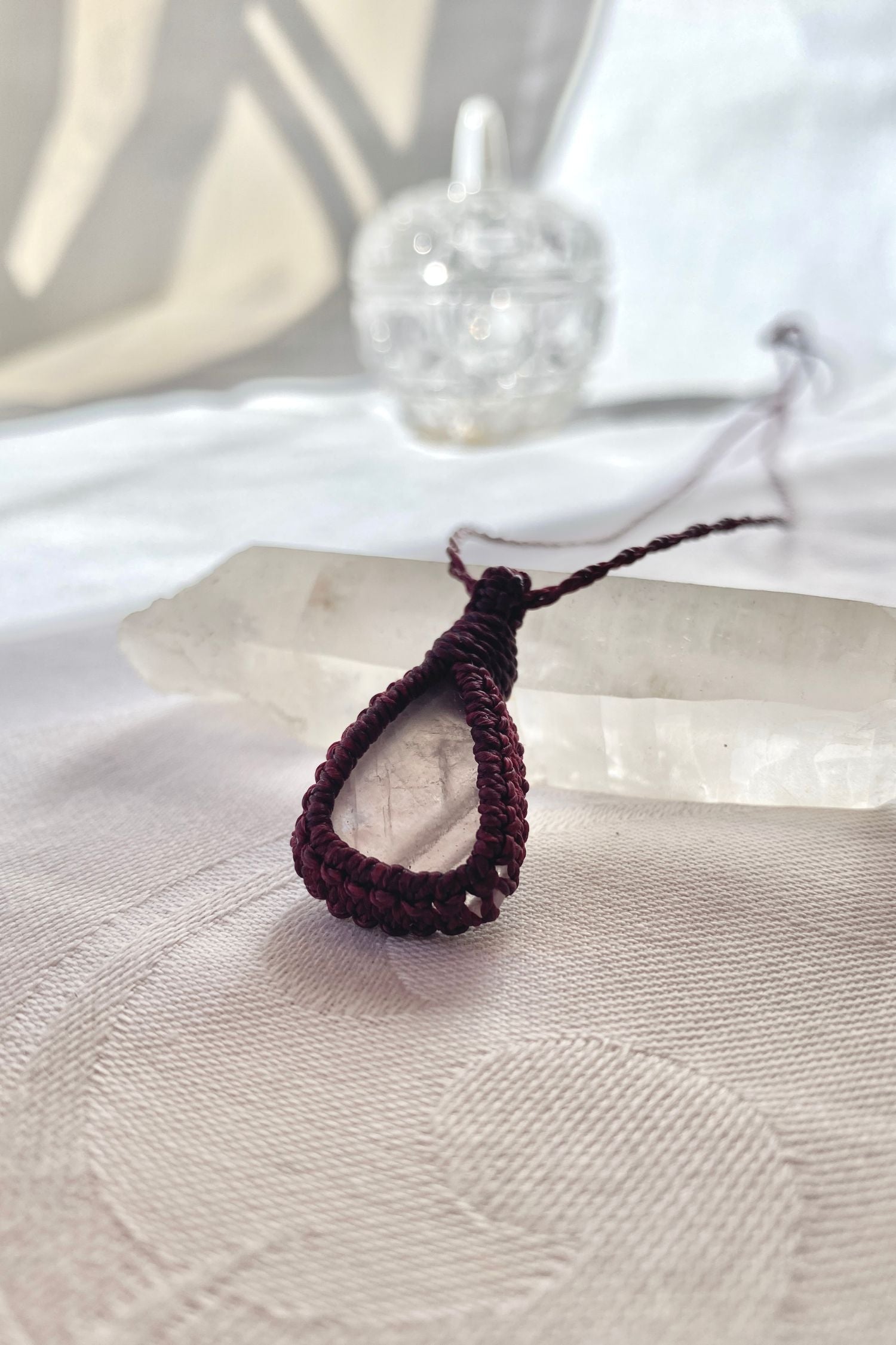 Another side angle shot of the rose quartz macrame necklace, showing the smooth, soft pink hues of the natural gemstone.