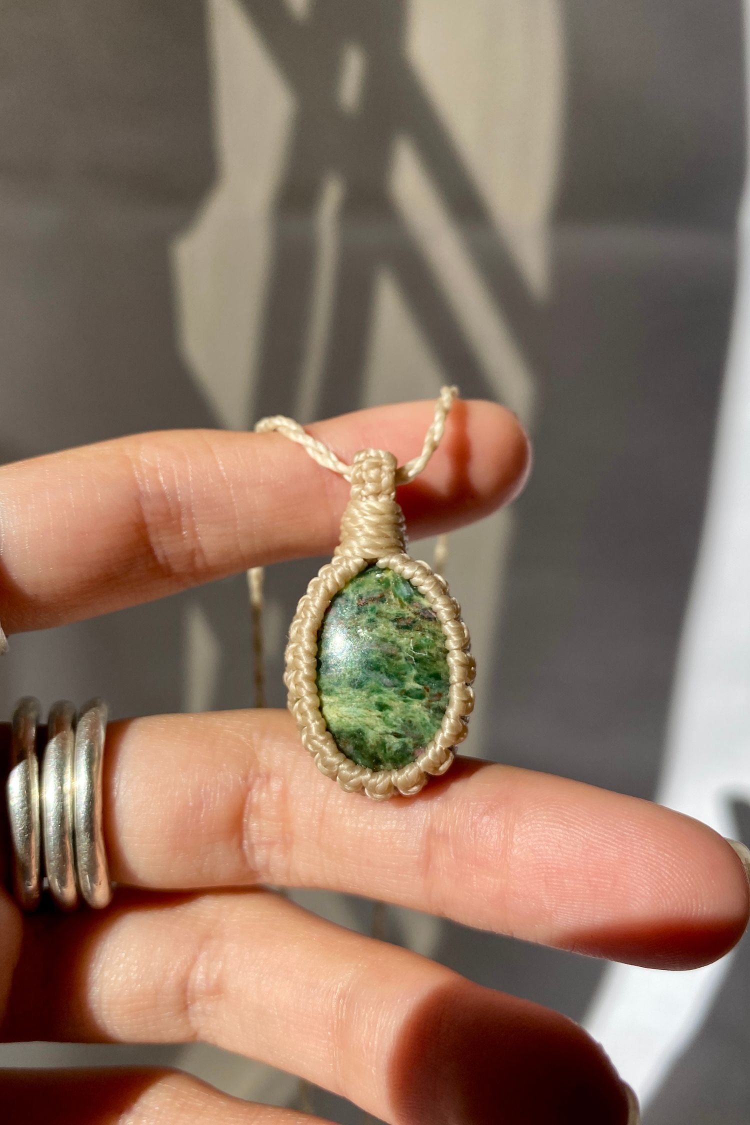 Hand holding a handmade Ruby Fuchsite Macrame necklace from the Essence collection, featuring a high-quality natural gemstone in a delicate everyday-wear design.