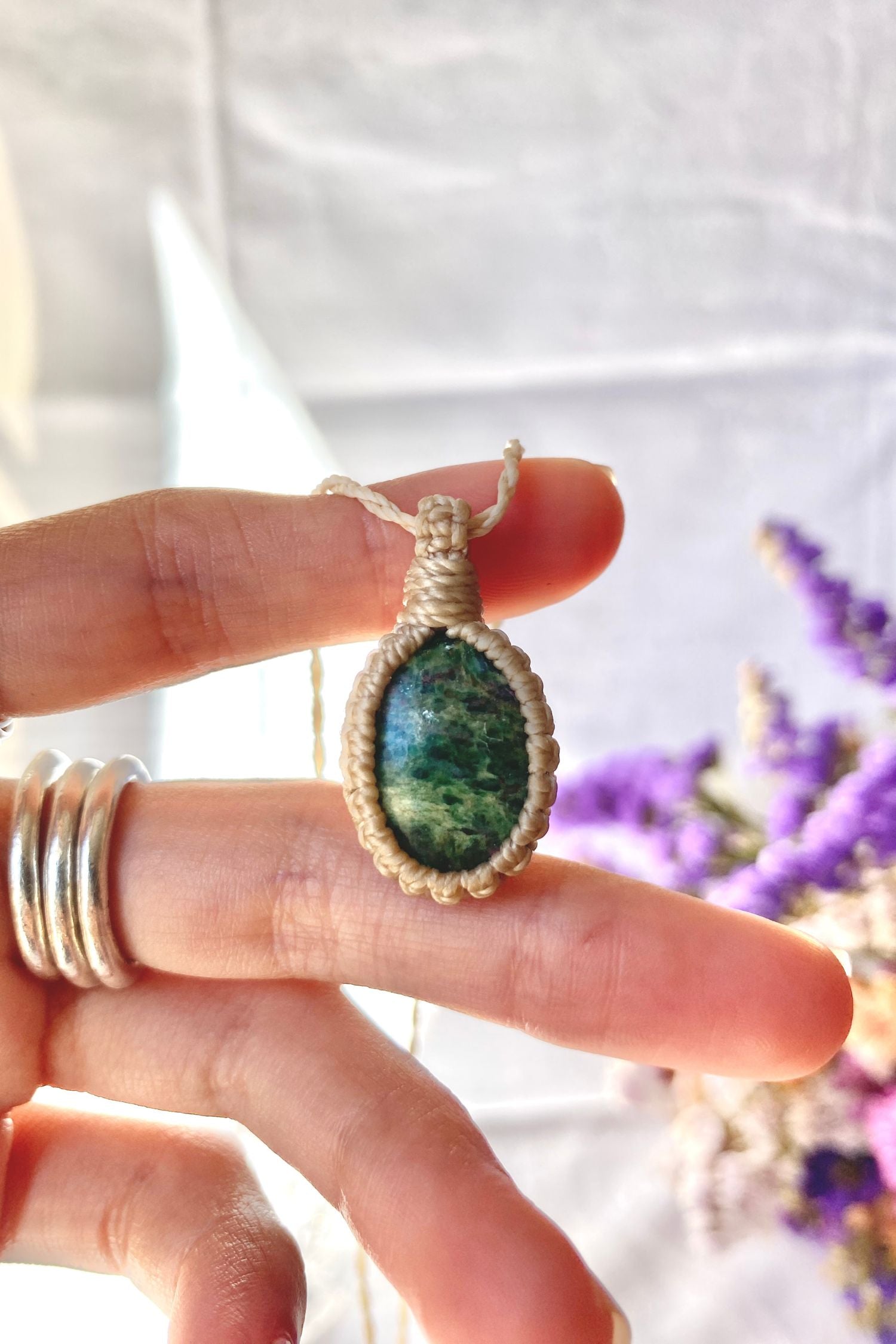 Close-up of handmade Ruby Fuchsite Macrame necklace in hand, showcasing the intricate macrame knotting and the vibrant colors of the gemstone.