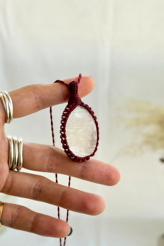 Hand holding a handmade Selenite Macrame necklace from the Essence collection, featuring a high-quality gemstone in a delicate everyday-wear design.