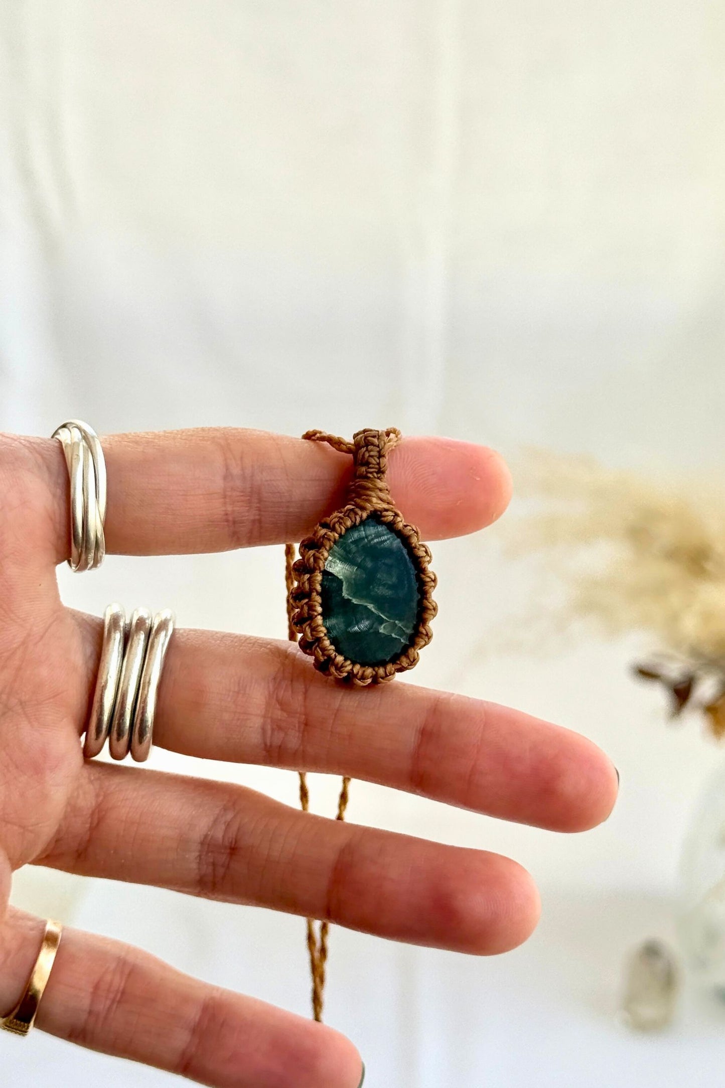 Hand holding a handmade Seraphinite Macrame necklace from the Essence collection, featuring a high-quality gemstone in a delicate everyday-wear design.