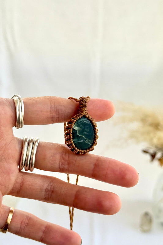 Hand holding a handmade Seraphinite Macrame necklace from the Essence collection, featuring a high-quality gemstone in a delicate everyday-wear design.