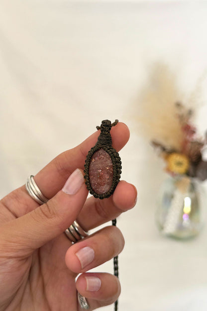 Close-up of handmade Sunstone Macrame necklace in hand, showcasing the intricate macrame knotting and the vibrant sparkly hues of the gemstone.