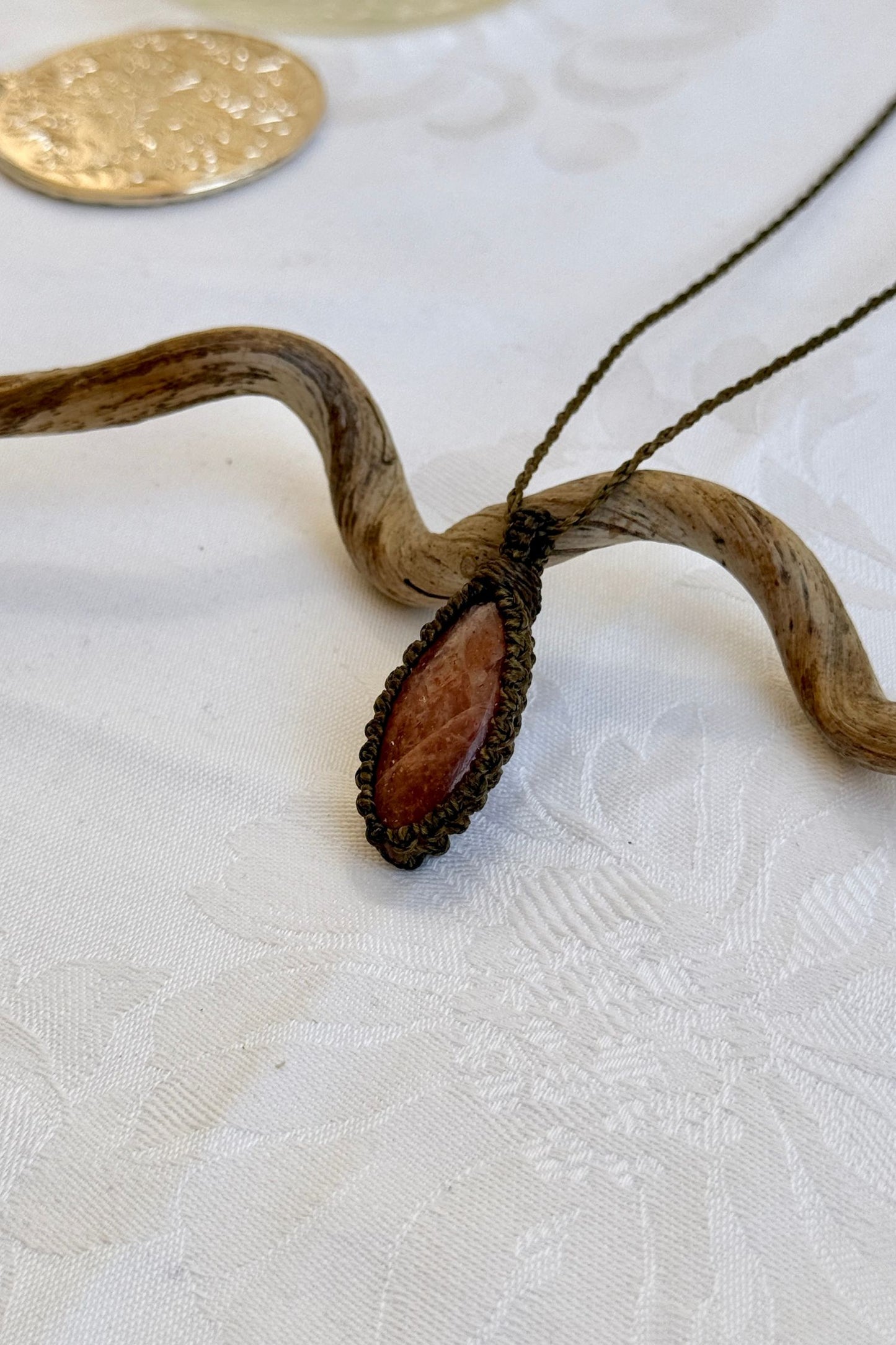 Side angle view of the Sunstone Macrame necklace, showing the fine macrame details and the unique gemstone centerpiece.