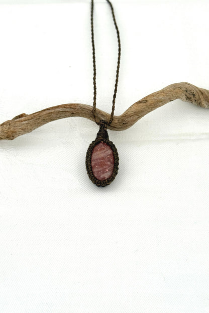 Handmade Sunstone macrame necklace with a dark green cord, laid flat to display its intricate design and glowing gemstone.