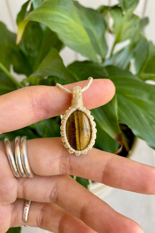 Hand holding a handmade Tiger’s Eye macrame necklace, showcasing the gemstone’s warm golden-brown hues and natural chatoyancy.