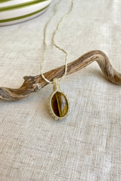 Side angle view of a handmade Tiger’s Eye macrame necklace, showcasing the detailed macrame design and gemstone’s rich golden hues.