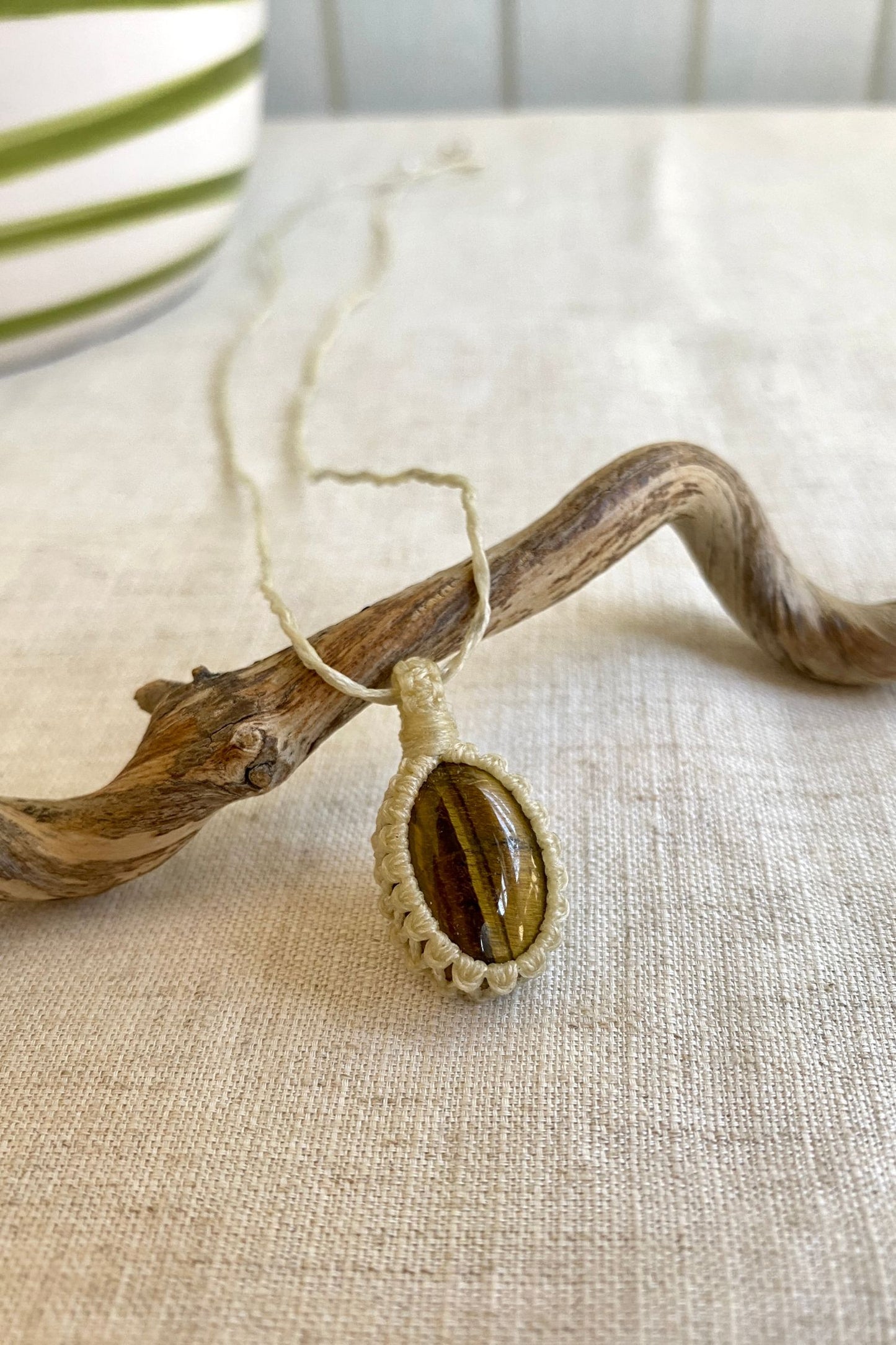 Close-up side angle of a handmade Tiger’s Eye macrame necklace, emphasizing the gemstone’s natural chatoyancy and unique color patterns.