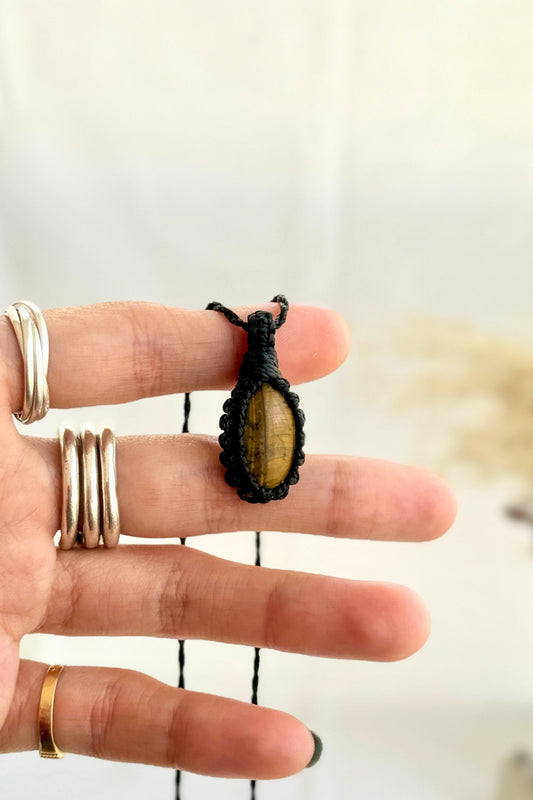 Hand holding a handmade Tiger’s Eye Macrame necklace from the Essence collection, featuring a high-quality gemstone in a delicate everyday-wear design.