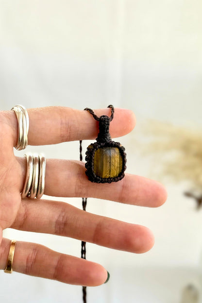 Hand holding a handmade Tiger’s Eye Macrame necklace from the Essence collection, featuring a high-quality gemstone in a delicate everyday-wear design.