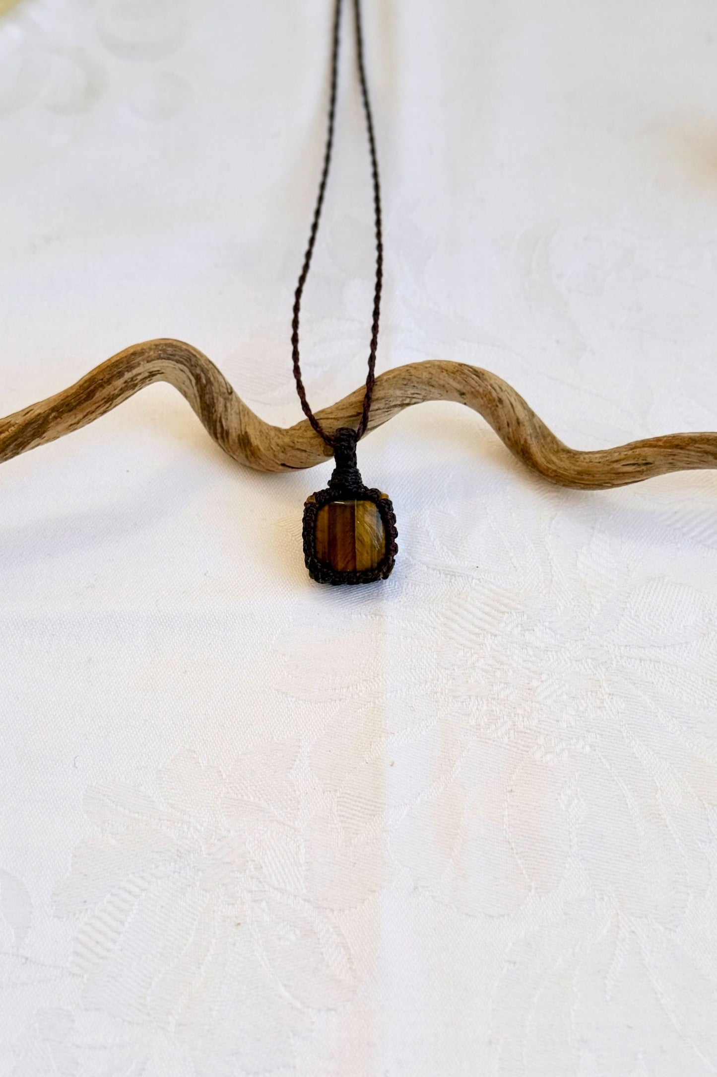 Handmade Tiger’s Eye Macrame necklace featuring a high-quality gemstone, laid flat to showcase its delicate everyday-wear design from the Essence collection.