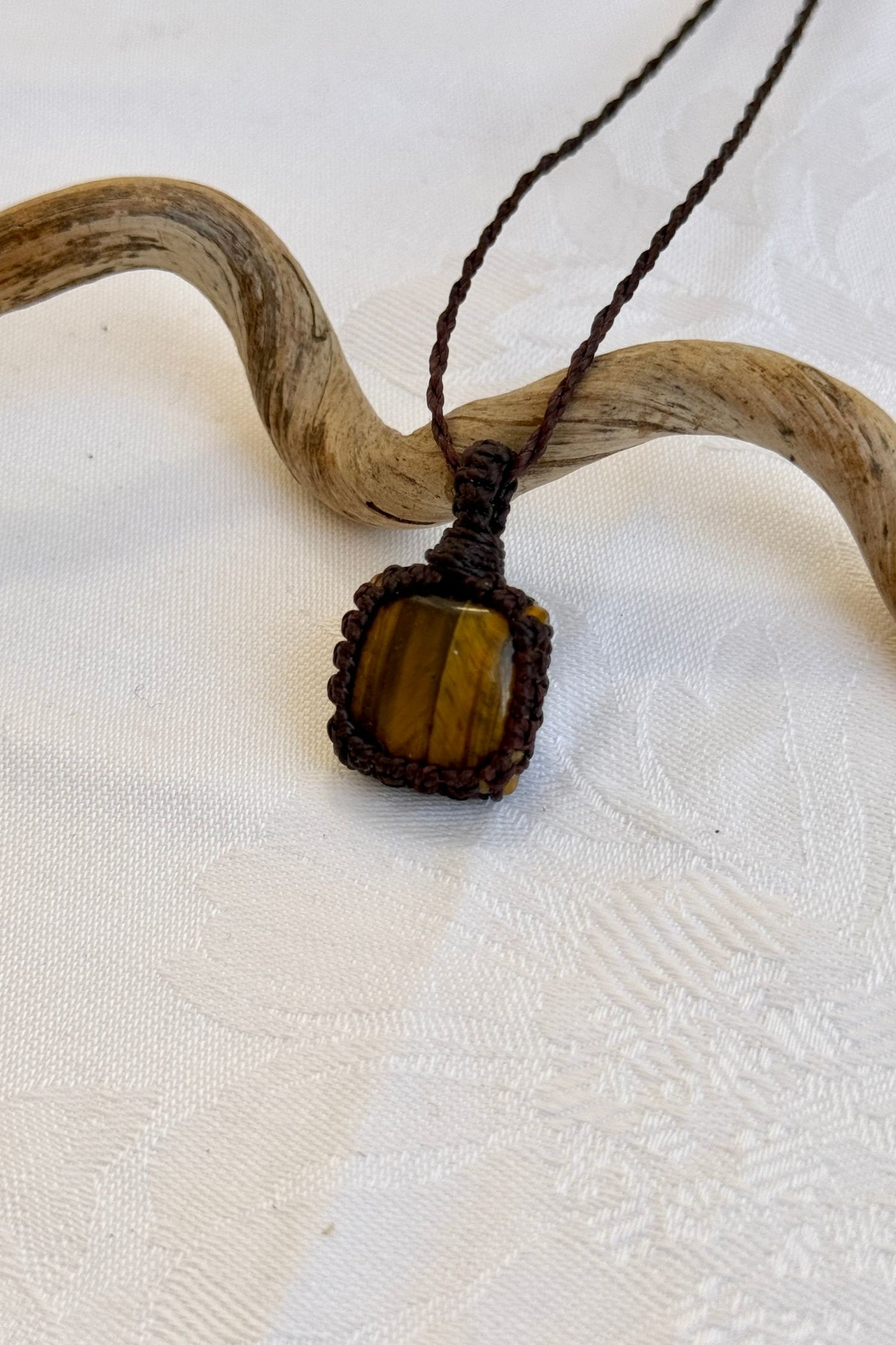 Close-up of handmade Tiger’s Eye Macrame necklace, showcasing the intricate macrame knotting and the vibrant patterns of the gemstone.