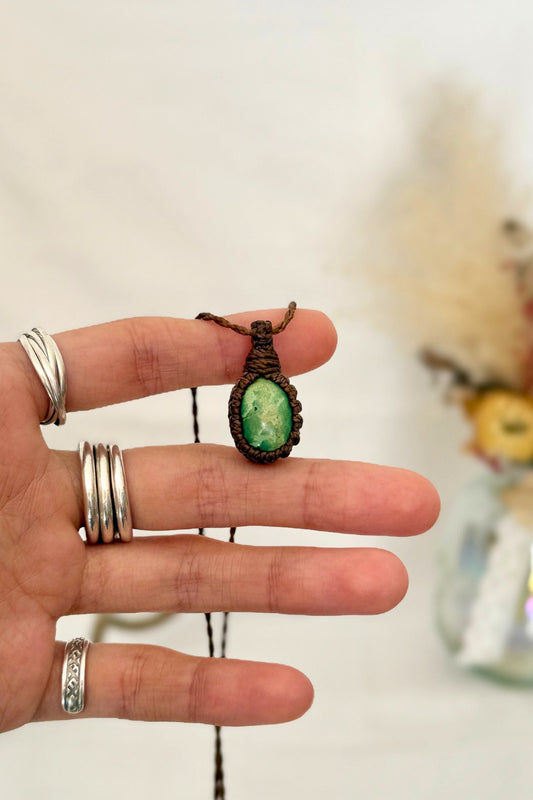 Hand holding a handmade Turquoise Macrame necklace from the Essence collection, featuring a high-quality green gemstone in a delicate everyday-wear design.