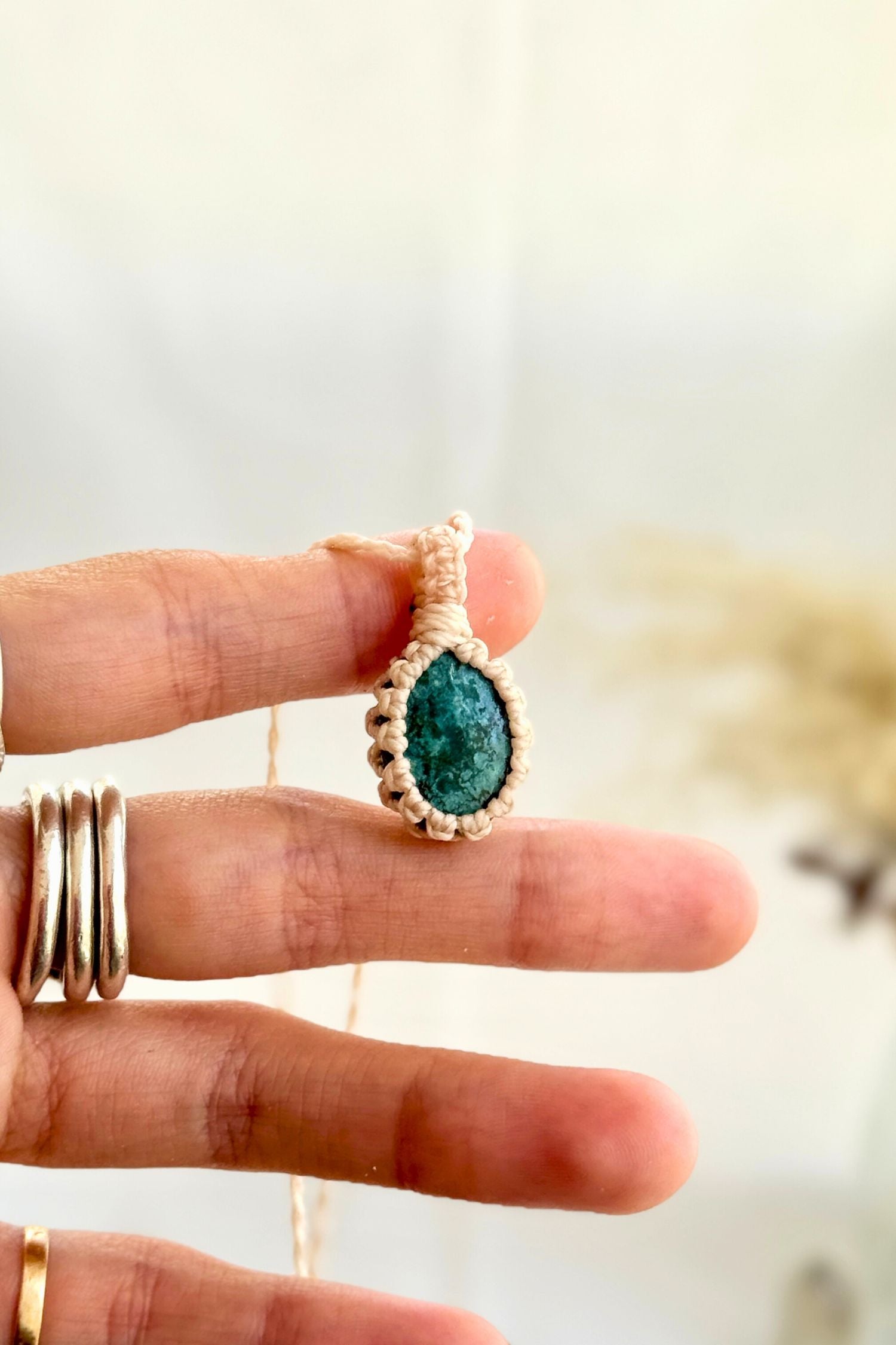Hand holding a handmade Turquoise Macrame necklace from the Essence collection, featuring a high-quality gemstone in a delicate everyday-wear design.