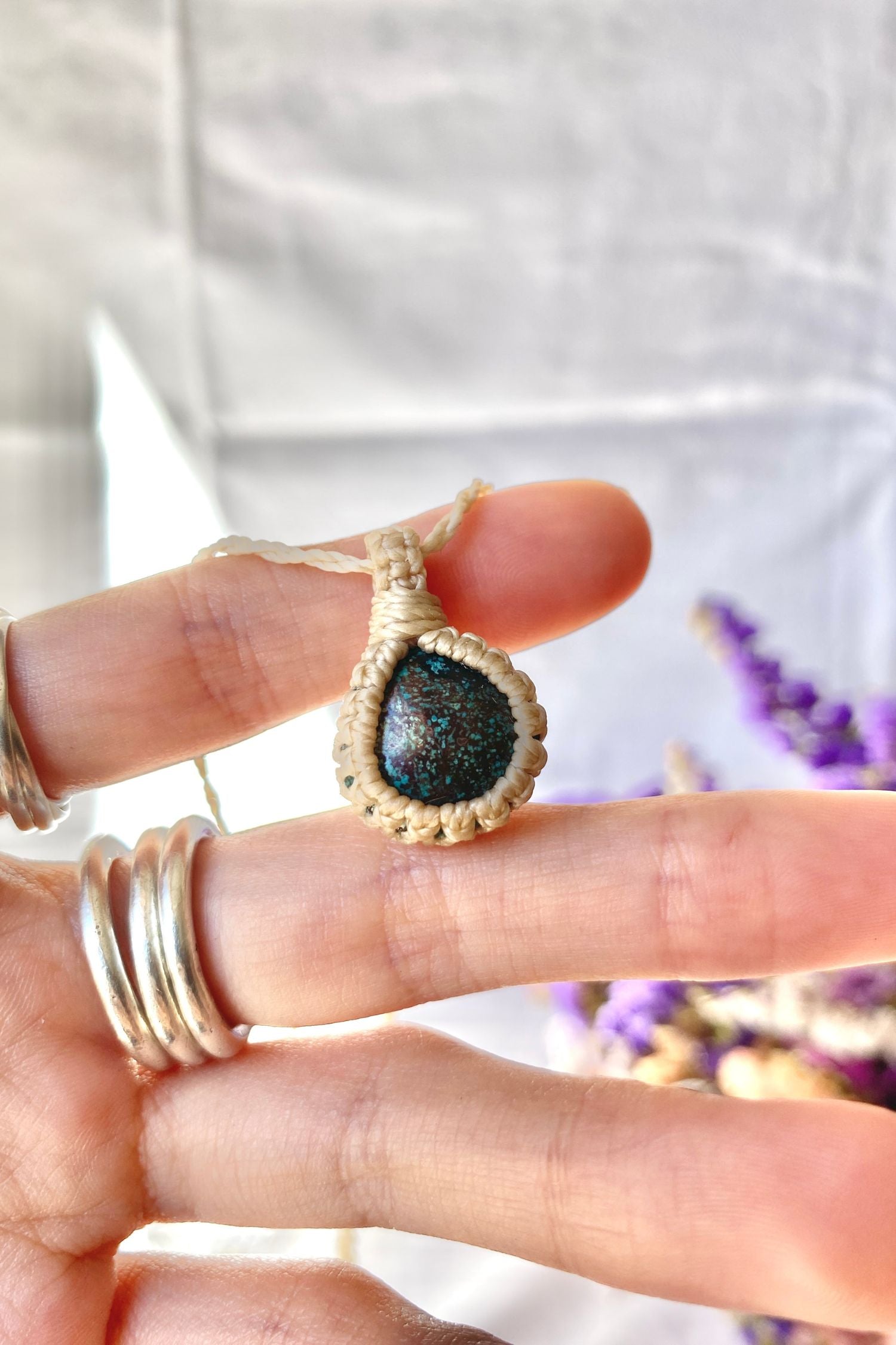 Close-up of handmade Turquoise Macrame necklace in hand, showcasing the intricate macrame knotting and the vibrant blue details of the gemstone.
